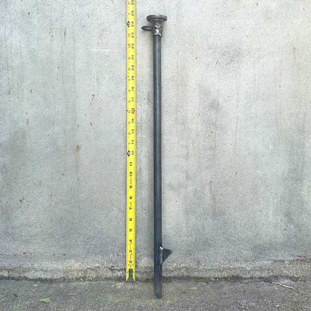 A 24 inch silver-colored cold rolled steel stake for securing dog leads, standing next to a yellow measuring tape which shows a height of 24 inches.