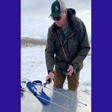 Load image into Gallery viewer, Man preparing to use the Beamer antenna on a cold winter day. Snow on ground and man is also wearing 2 of the dogsRtreed cable leashes and a dogsRtreed ball cap that is hunter green and tan in color. 