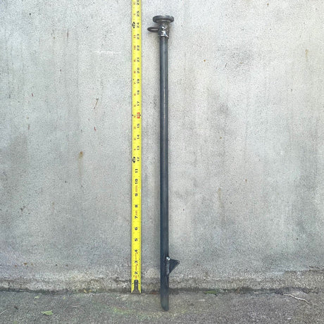 A 24 inch silver-colored cold rolled steel stake for securing dog leads, standing next to a yellow measuring tape which shows a height of 24 inches.