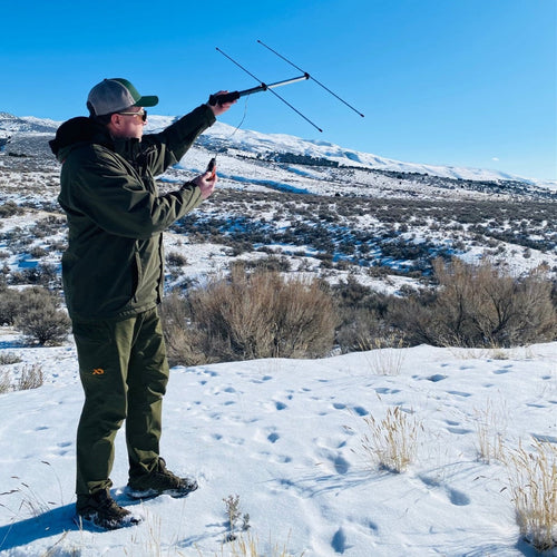 Beamer directional antenna being held and used by man in winter gear on snowy hillside. 